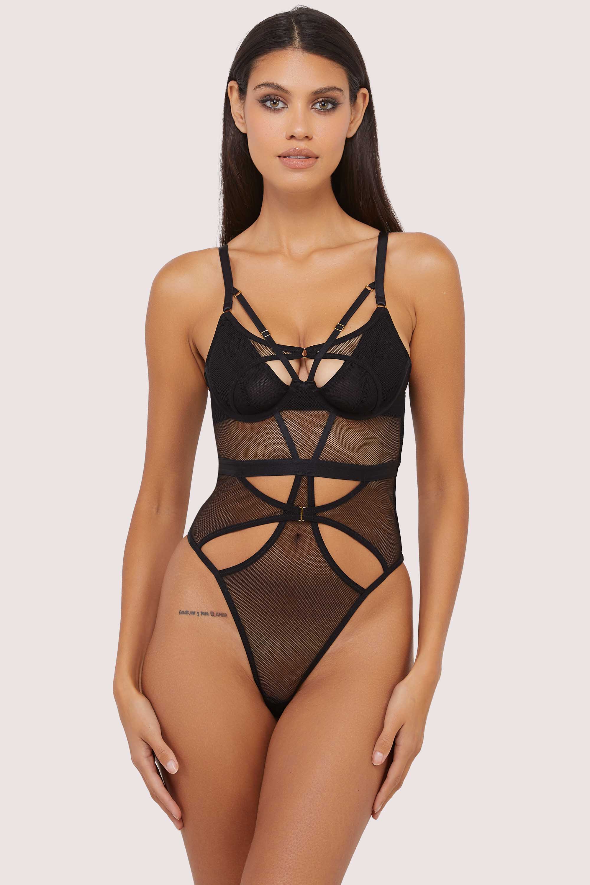 Model wears Black Micro Fishnet Body featuring underwired plunge cups, gold hardware, and intricate harness strap details.