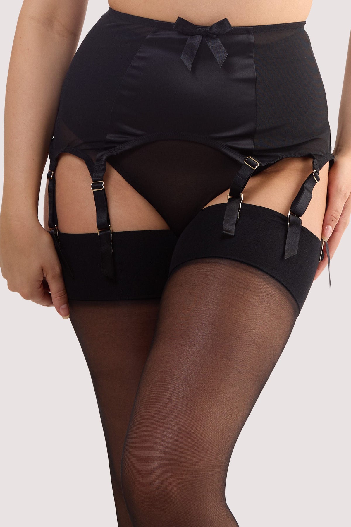 Model wears a black satin 8 Strap retro everyday suspender with six adjustable straps, soft and smooth finish with a matching brief.