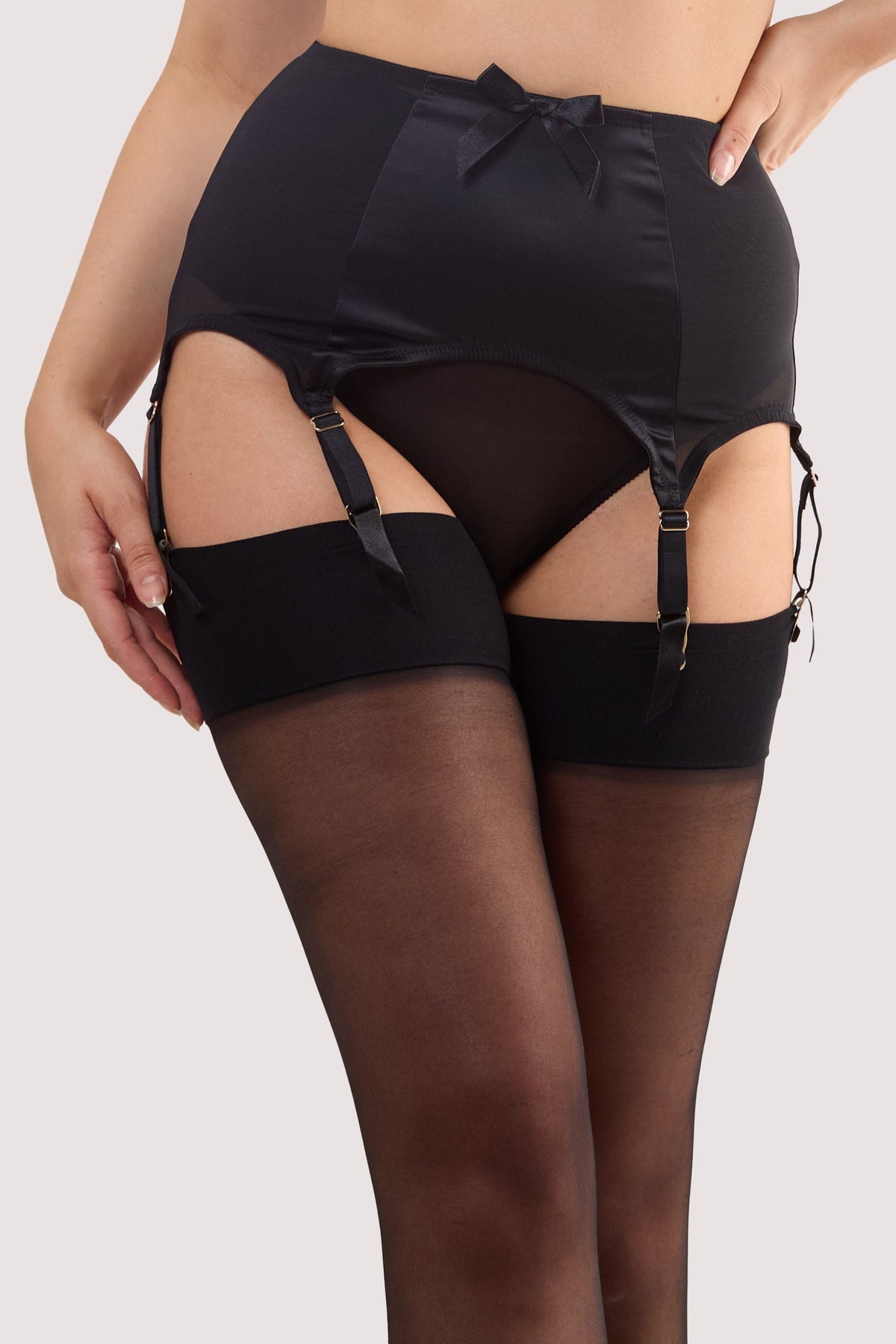 Model wears a black satin 6 Strap retro everyday suspender with eight adjustable straps, soft and smooth finish with a matching brief.
