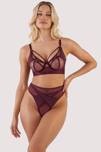 Harness style crossover thong with mesh overlay and visible gold hardware in a deep wine red/purple, worn with matching bra.