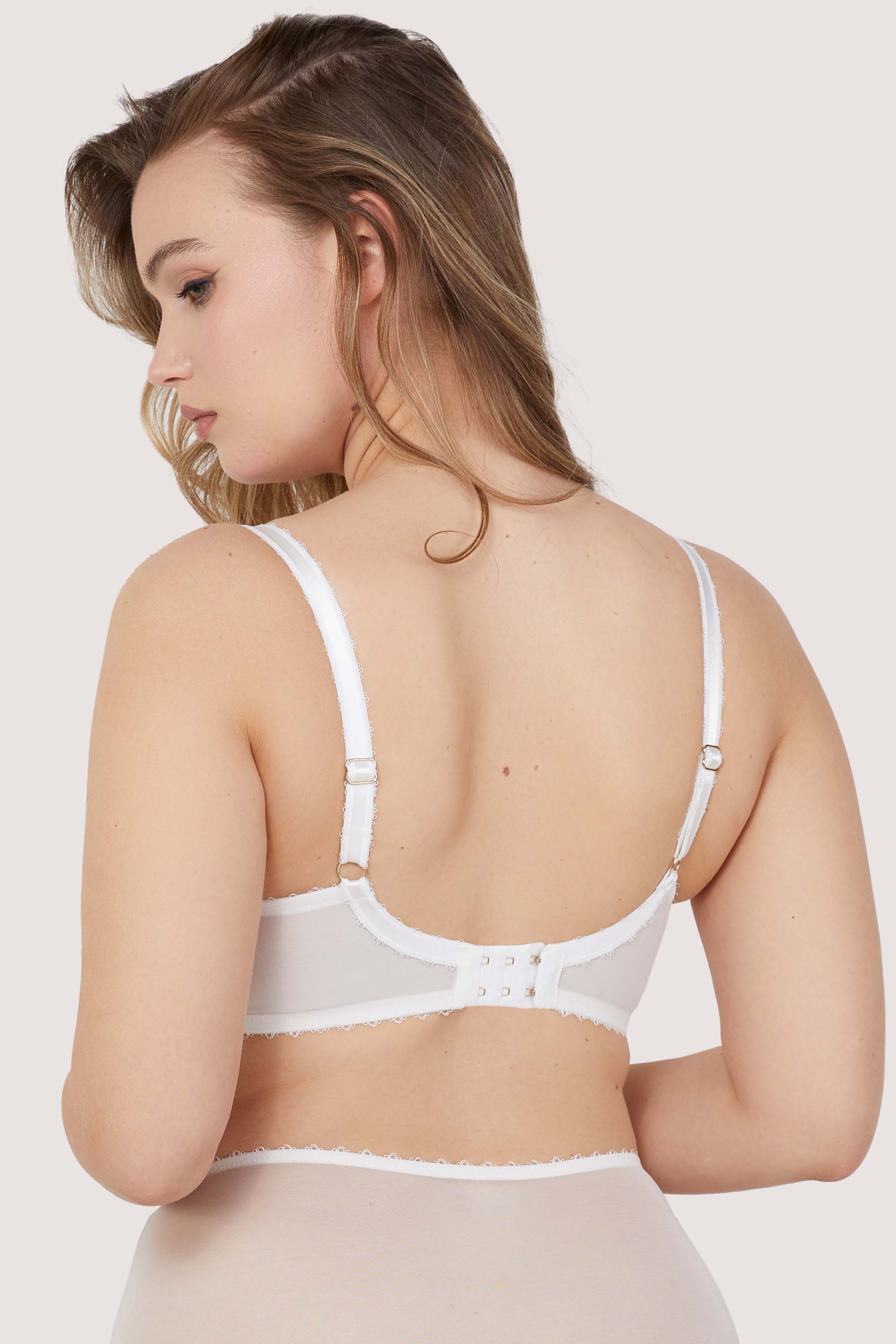 Model shows adjustable shoulder straps and hook and eye fastening back of white broderie anglaise balconette bra