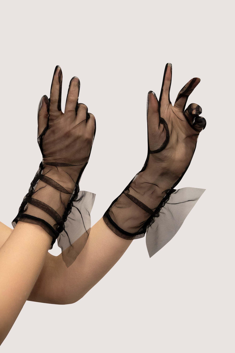 Model wears black sheer mesh gloves with wrist frill