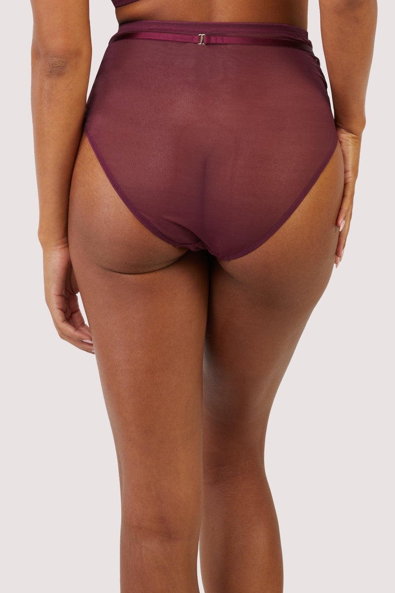 Back view of a harness style brief with mesh overlay and visible gold hardware in a deep wine red/purple.