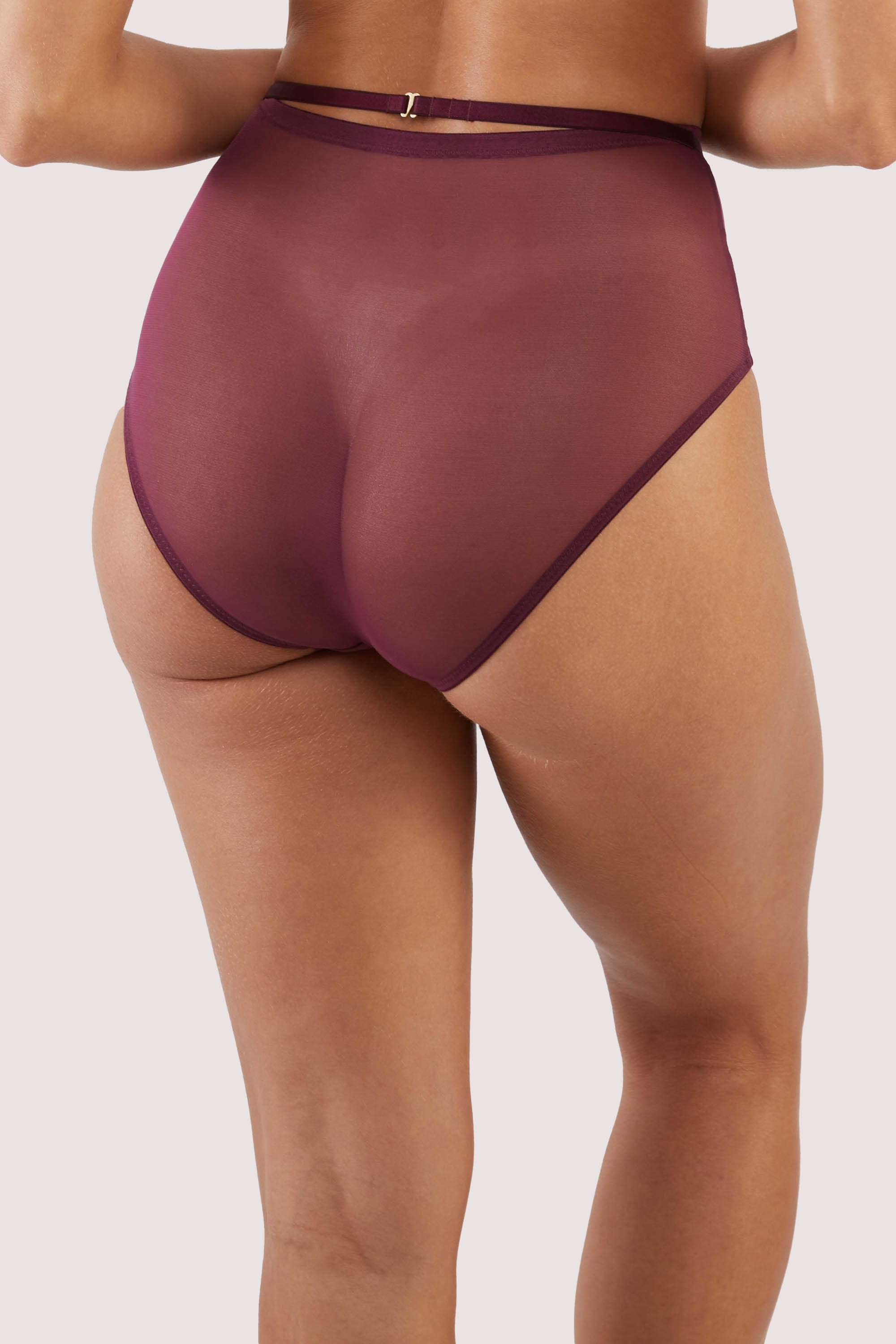 Back view of a harness style brief with mesh overlay and visible gold hardware in a deep wine red/purple.