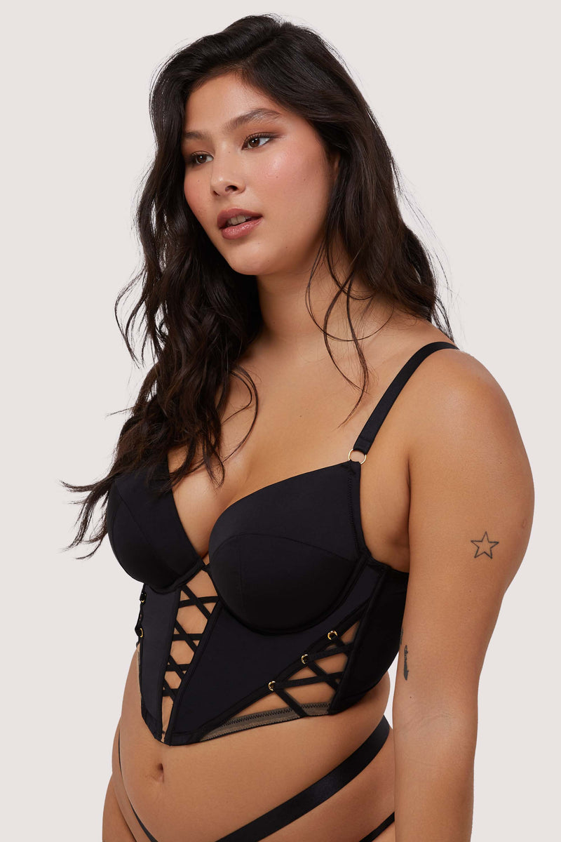 Model wears black lace-up boned bustier with shoulder straps and underwire cups