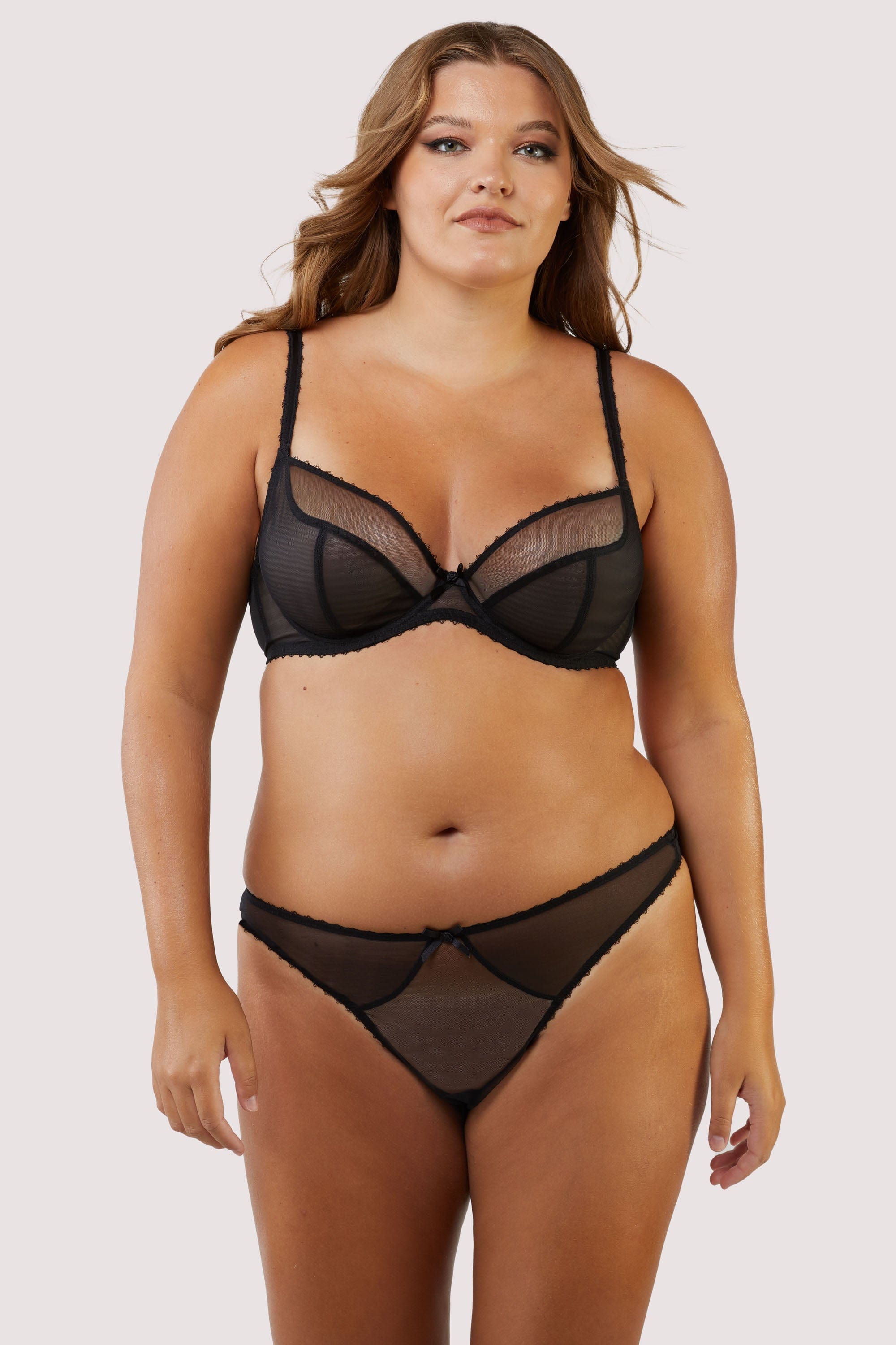 Model in black mesh bra and panties, featuring adjustable straps and a low-cut design for comfort and style.