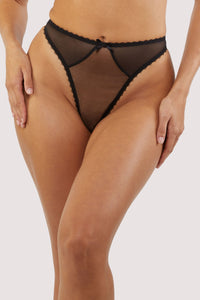 Model wears a sheer black thong with mesh panels and a bow detail, highlighting its blend of comfort and elegance.