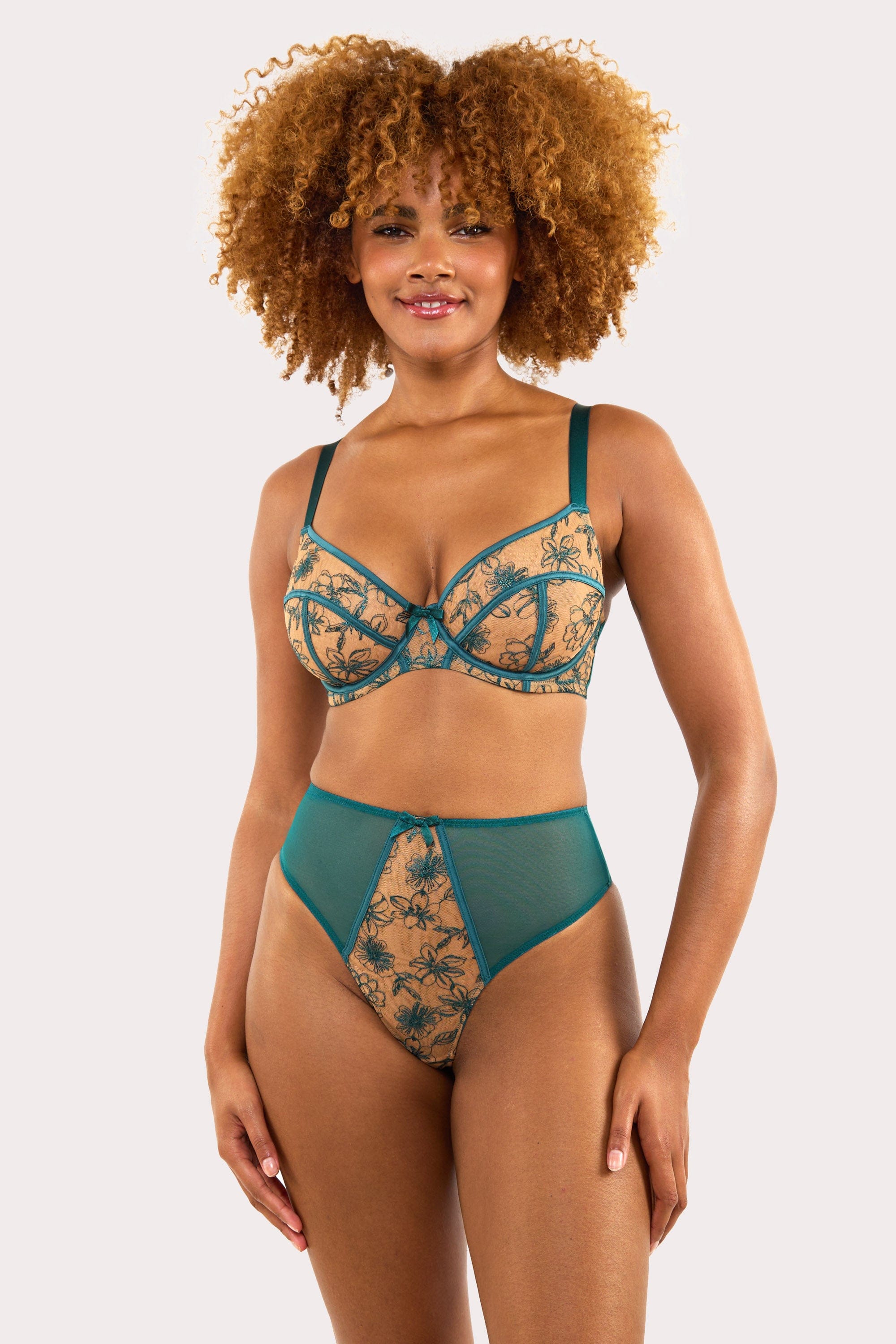 Model wears a teal contrast embroidery balconette bra and high waisted Thong set featuring nude mesh and teal floral detailing
