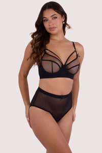 Model wears black mesh D+ bra and matching high-waist thong, featuring sheer black mesh and harness strap detailing