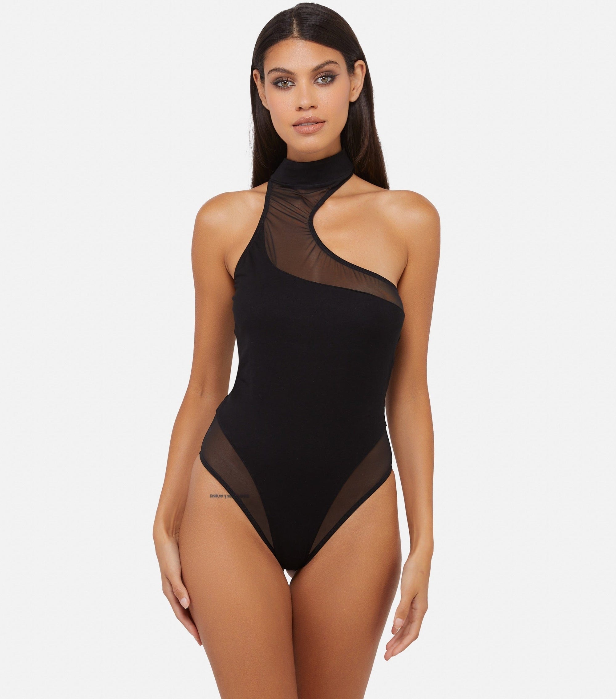 Model wearing black asymmetric thong bodysuit with mesh and jersey paneling and high neckline