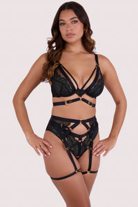 Fuller bust model wears dark green wet look lace lingerie with a matching strappy harness suspender belt featuring gold hardware