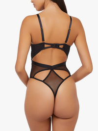 Model shows back of Black Micro Fishnet Bodysuit with harness straps, mesh panels, and thong-style bottom